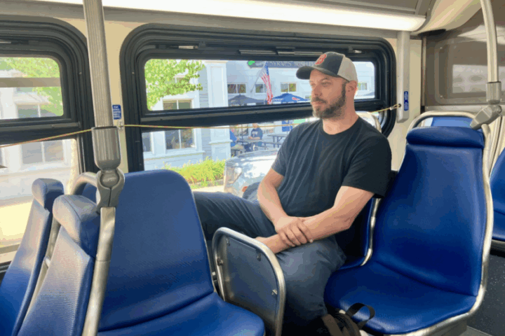 A adult male sitting in a city bus
